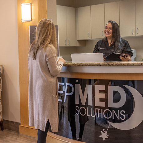 Woman checking in at front desk of sleep office