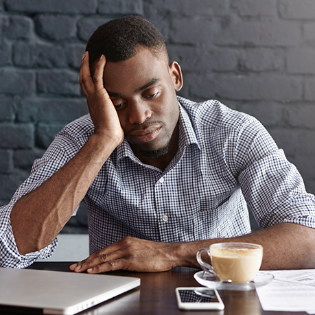 Tired man sitting at desk and resting his head in his hand