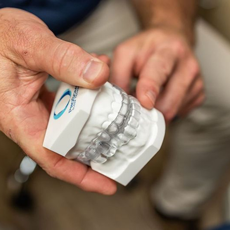 Dentist holding a model of the teeth with clear oral appliances in Greensboro