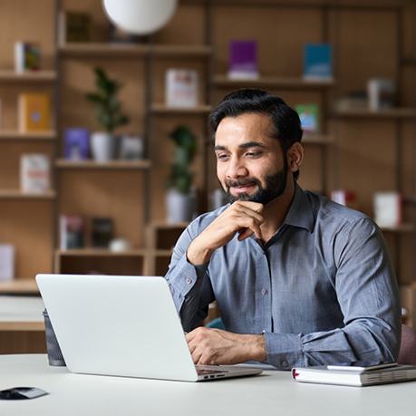 Man smiling while looking at his laptop