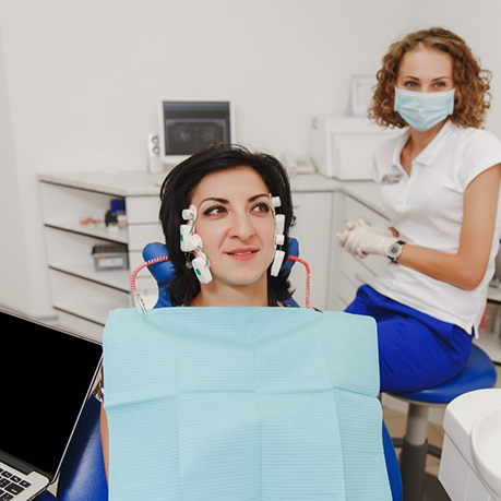 Woman in dental chair with small sensors attached to the sides of her head