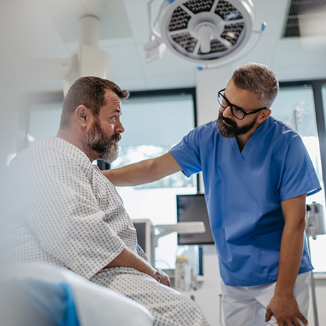 Man in a hospital gown talking to a doctor