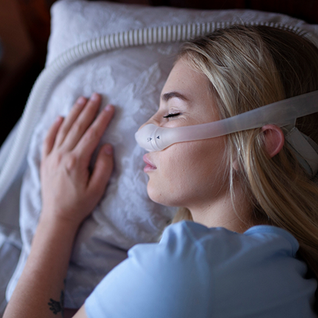 Woman sleeping on her side with a C P A P mask over her nose